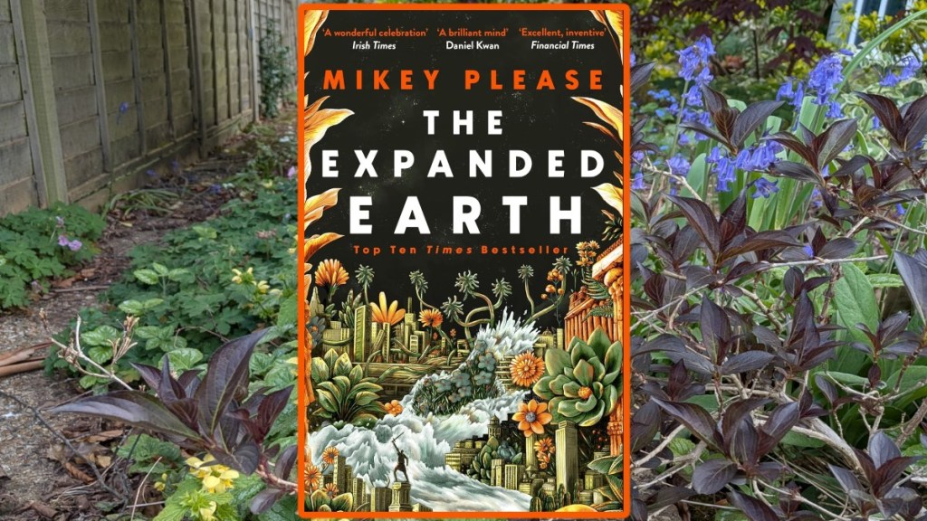 Cover of Mikey Please's The Expanded Earth ona background of a overgrown garden path with bluebells.