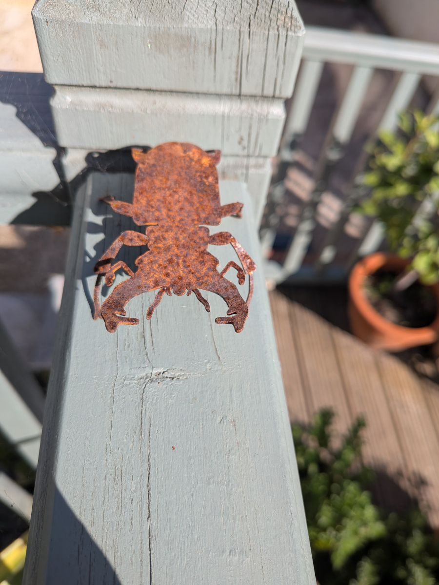A rusty metal stag beetlle on a fence.